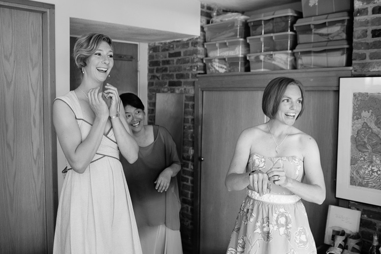 the mother of the bride and bridesmaids react to seeing bride in her dress