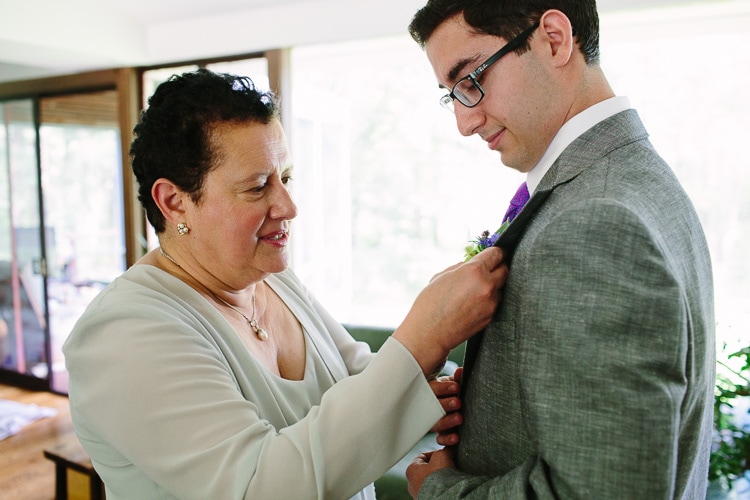 mother of the groom helps with a boutonniere