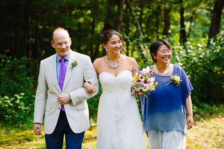 bride walks down the outdoor aisle with her parents
