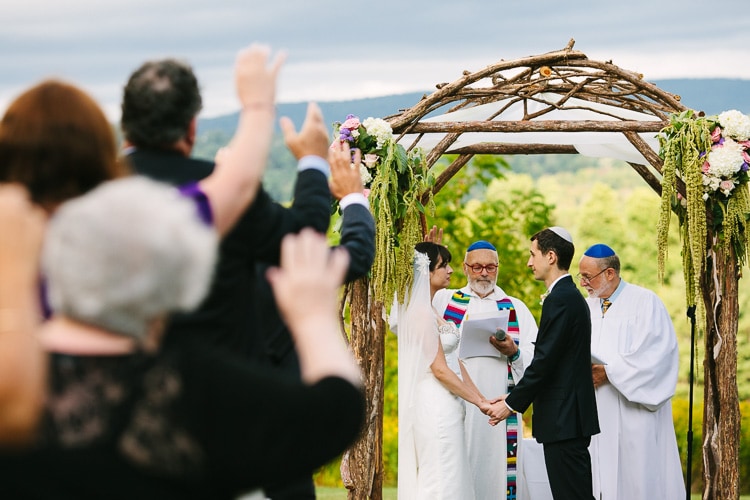 guests raise their hands in a blessing during an outdoor, interfaith wedding ceremony in the Berkshires
