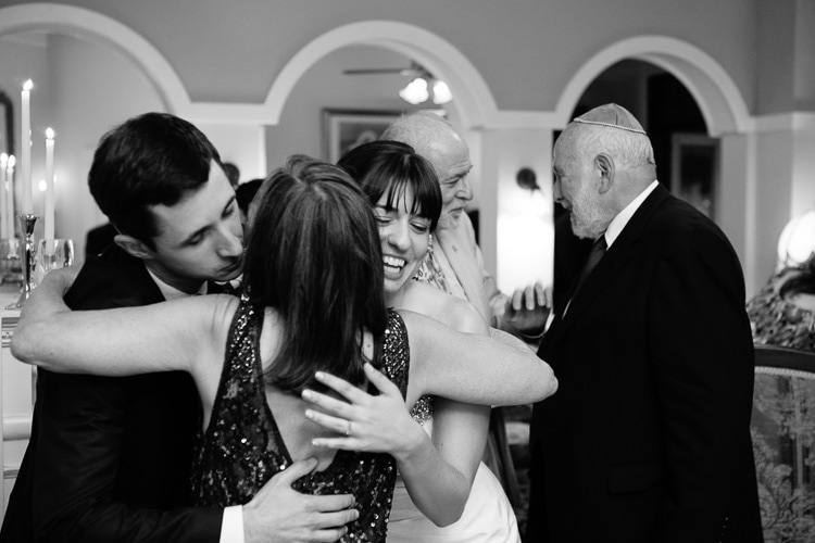 mother of the groom gets a hug from bride and groom during cocktail hour