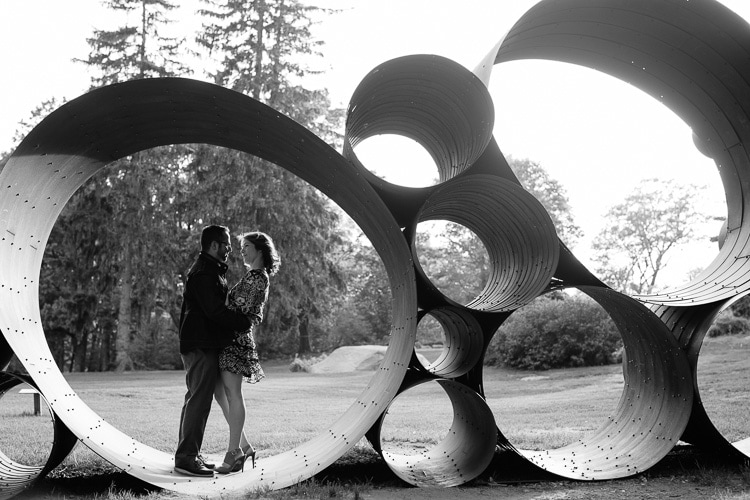black and white engagement portrait of a couple framed by sculpture at the DeCordova Sculpture Park 