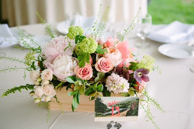 wedding detail of centerpiece in a wooden crate and vintage postcard table number