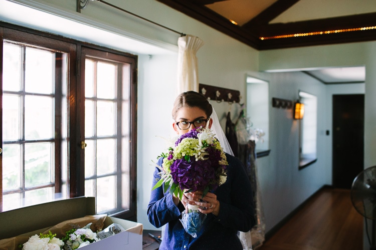 bride smells her bouquet while getting ready for her Willowdale Estate wedding, image by Kelly Benvenuto