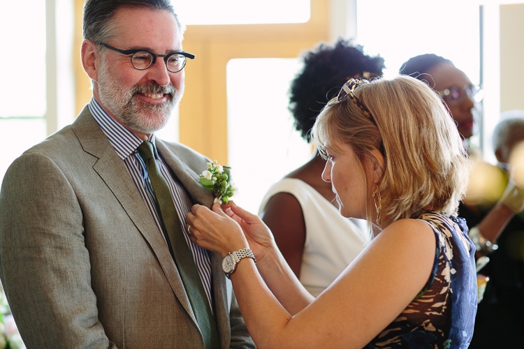 friend helps groom with boutonniere