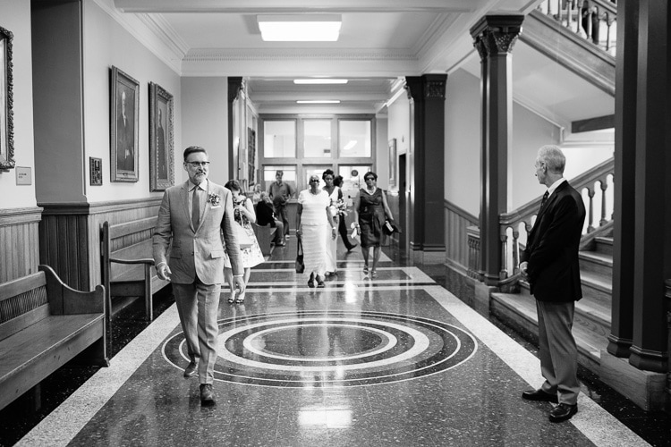 groom and guests walk to ceremony in Cambridge City Hall