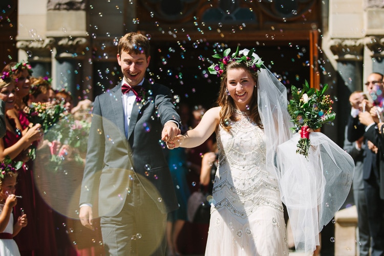 bride and groom exit church amid bubbles