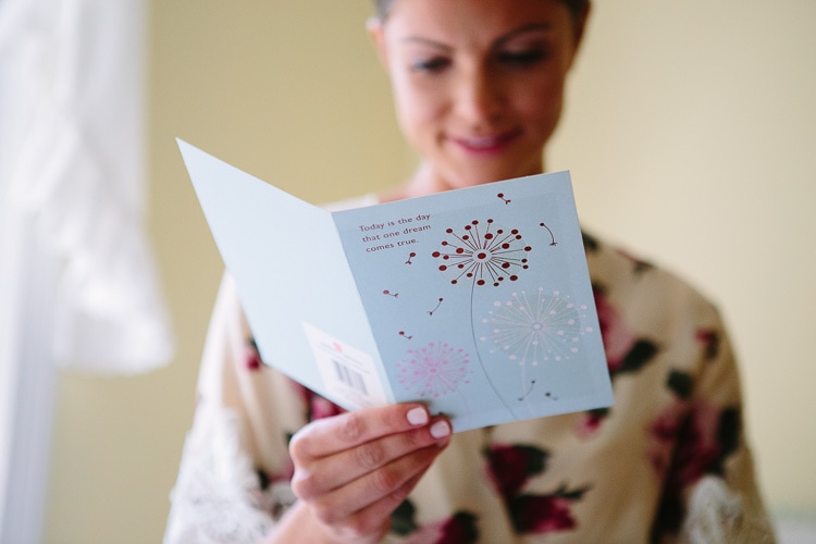 bride reads dreams come true wedding card while getting ready