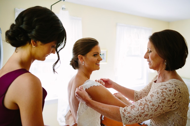 bride puts on dress with help from mother and sister