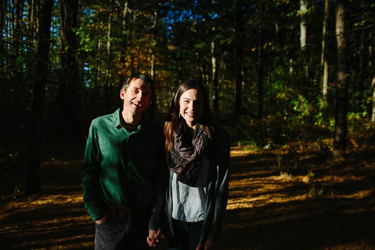 Relaxed engagement photo in dramatic light, in the woods of the Middlesex Fells. Image by Kelly Benvenuto.