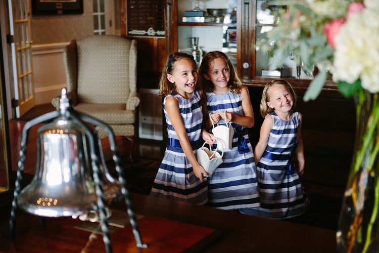 Flower girls wait to walk down the aisle at a wedding at the Corinthian Yacht Club in Marblehead, MA. Documentary wedding photography by Kelly Benvenuto.