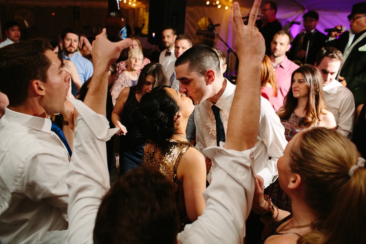 Bride and groom share a kiss on the dance floor during their wedding reception at Friendly Crossways, Harvard, MA. Vibrant, authentic wedding photography in Boston and New England by Kelly Benvenuto.