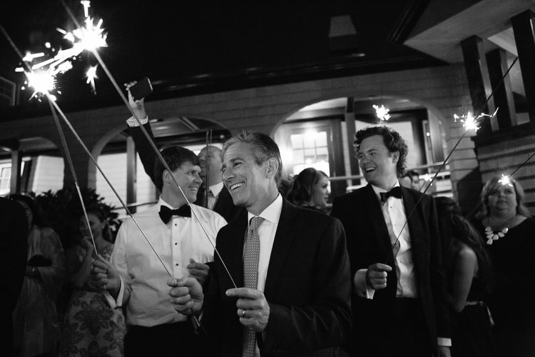 Guests hold sparklers waiting for the exit of the bride and groom from their reception at the Corinthian Yacht Club in Marblehead, MA. Black and white documentary wedding photography by Kelly Benvenuto.