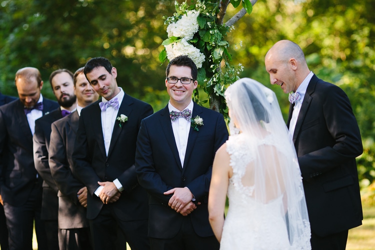 Groom smiles during outdoor wedding ceremony. Emotional Rhode Island wedding photographer Kelly Benvenuto.