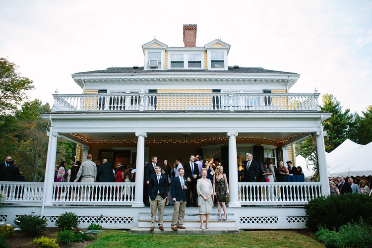 Wedding guests enjoy cocktail hour on the porch of the Pierce House in Lincoln, MA. Photo by Kelly Benvenuto.