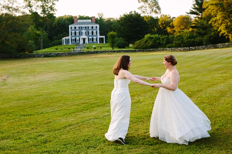 Happy, vibrant wedding portrait of an LGBT couple on the grounds of the Codman Estate in Lincoln, MA. Photograph by Kelly Benvenuto.