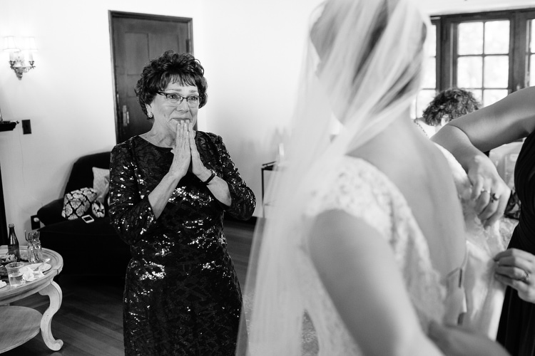 Mother of the bride tears up as her daughter dons her wedding gown. Emotional, authentic image by Boston wedding photographer Kelly Benvenuto.