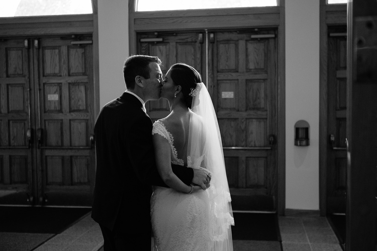 Bride and groom share a kiss in the vestibule of the church following their wedding ceremony in Duxbury, MA. Documentary wedding photography in Boston and New England by Kelly Benvenuto.