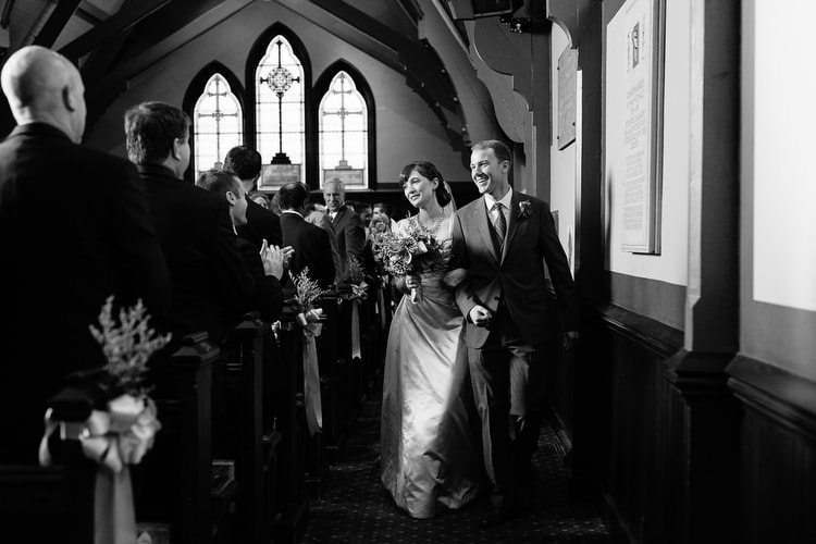 Joyful wedding couple comes up the aisle at the end of their wedding ceremony. Classic, black and white wedding photography by Kelly Benvenuto, serving Boston and New England.