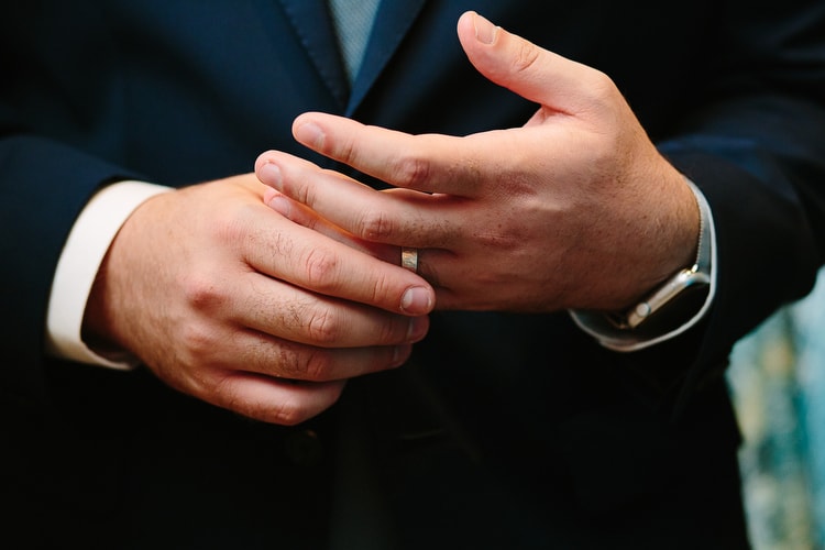 Groom gets used to his new wedding ring during the reception. Authentic wedding photography. by Kelly Benvenuto.