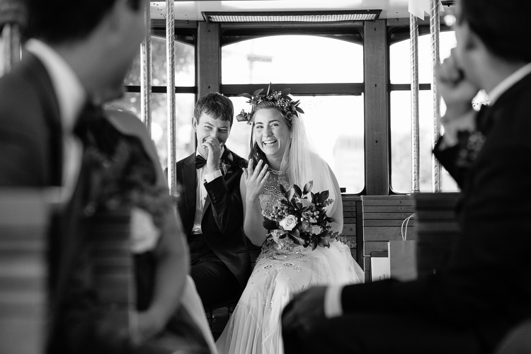 Bride and groom share a laugh in the trolley on the way from their wedding ceremony to reception. Emotional and candid wedding photography by Boston wedding photographer Kelly Benvenuto.