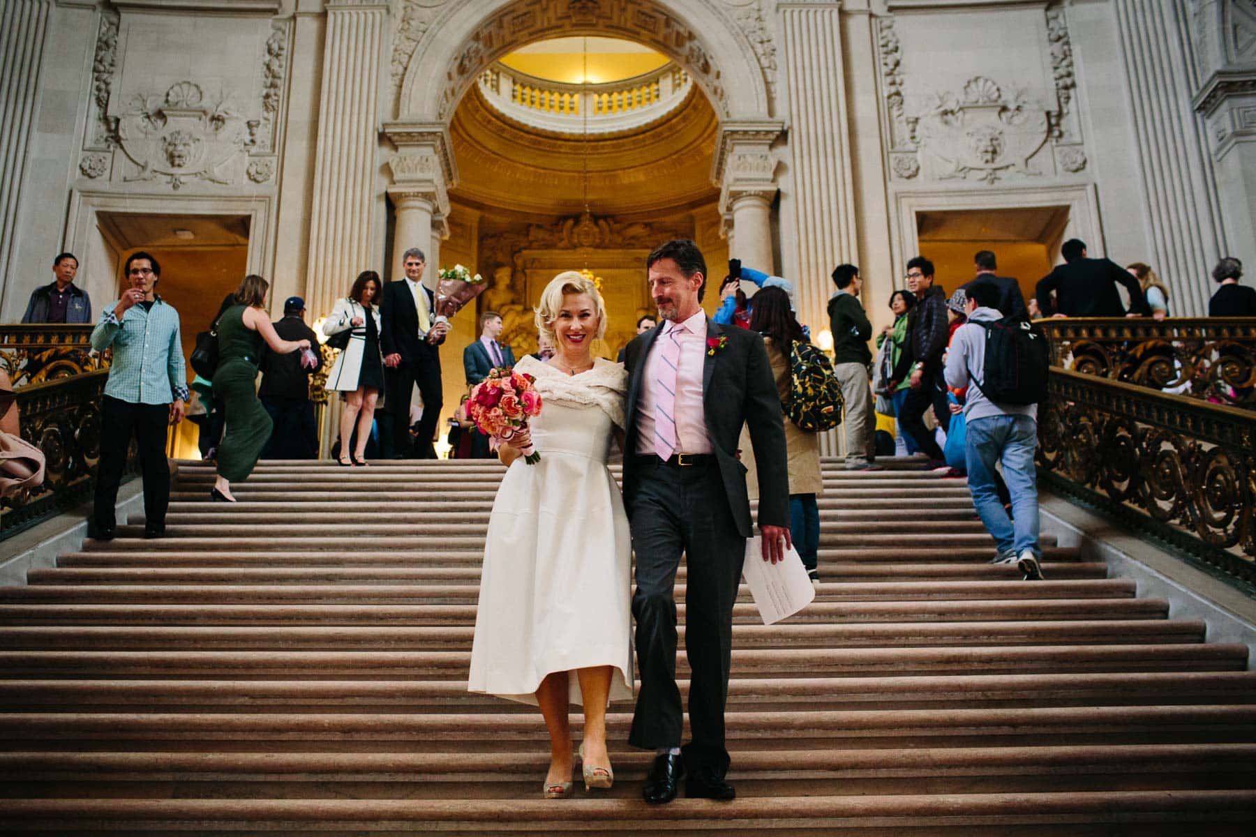 bride and groom descend steps after marriage ceremony at San Francisco City Hall