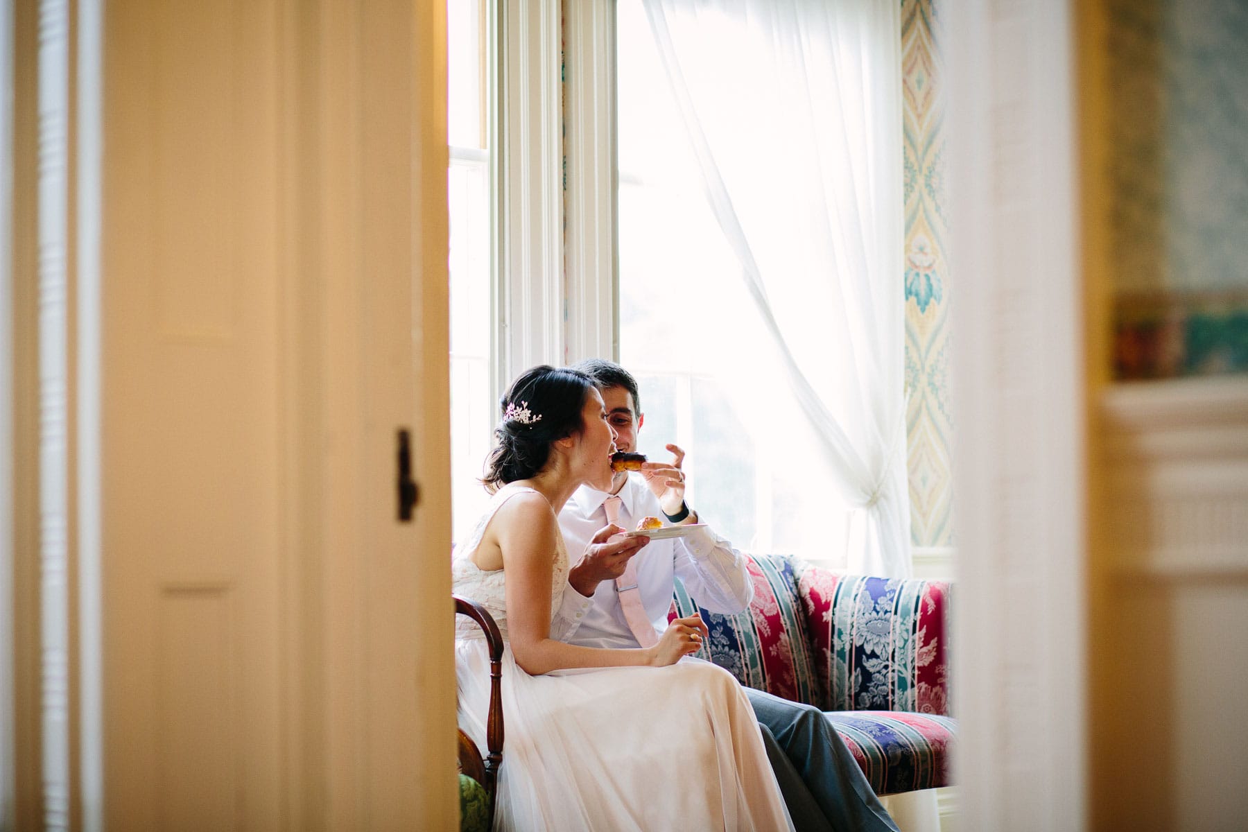 groom feeds bride a donut in a quiet moment away from their reception