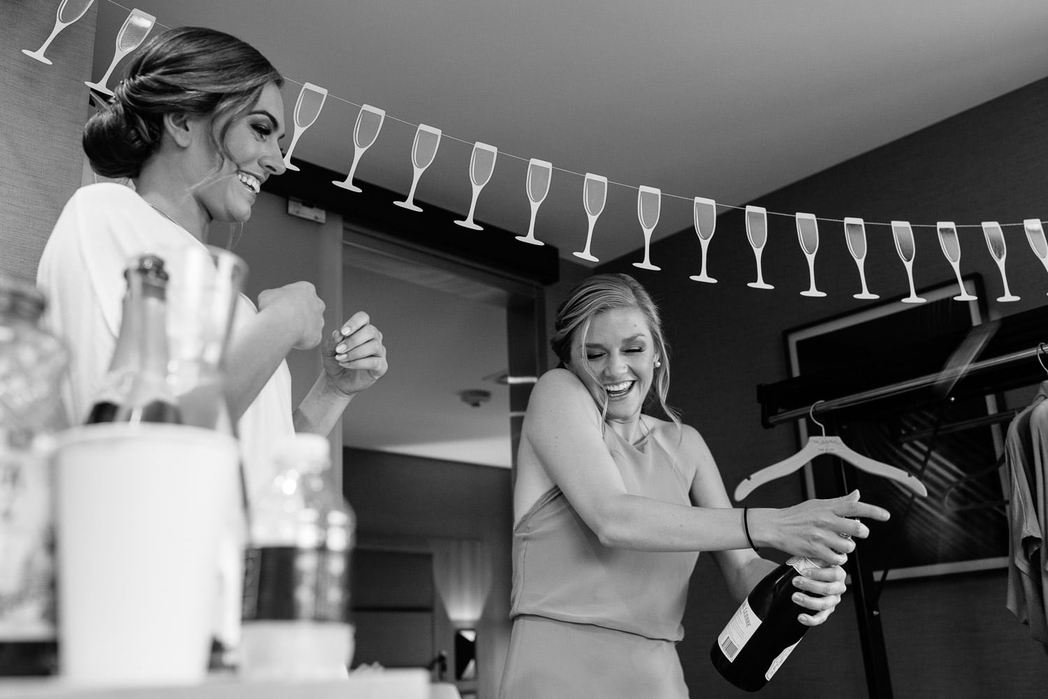 bridesmaid pops the champagne while getting ready