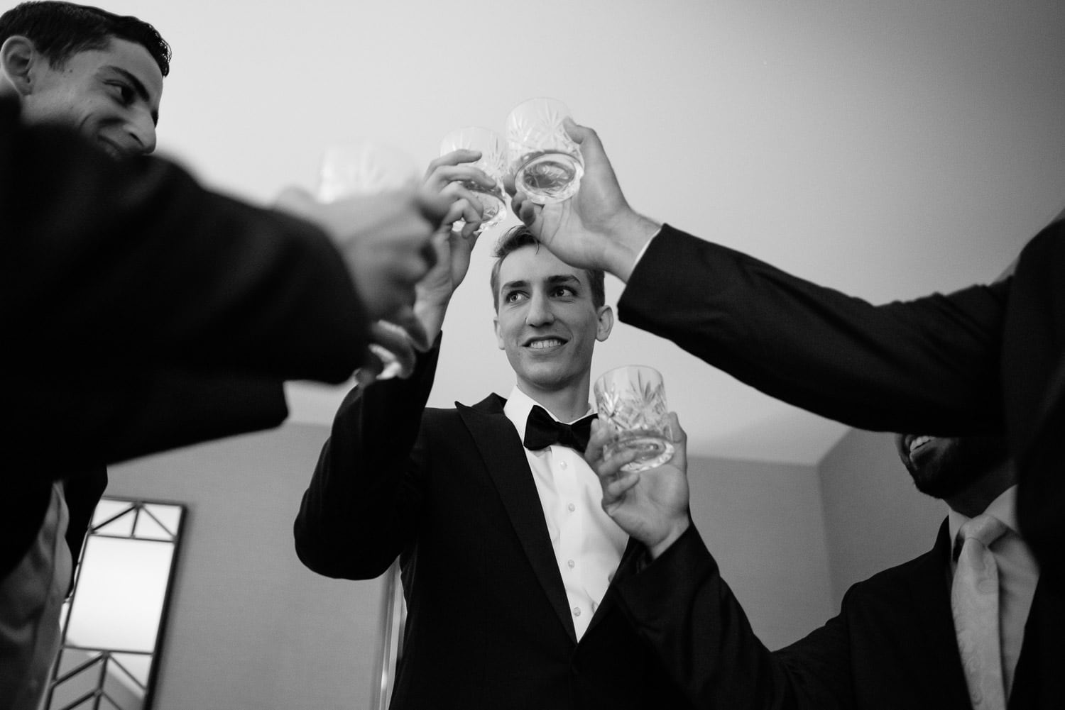 groom and groomsmen raise their glasses in a toast