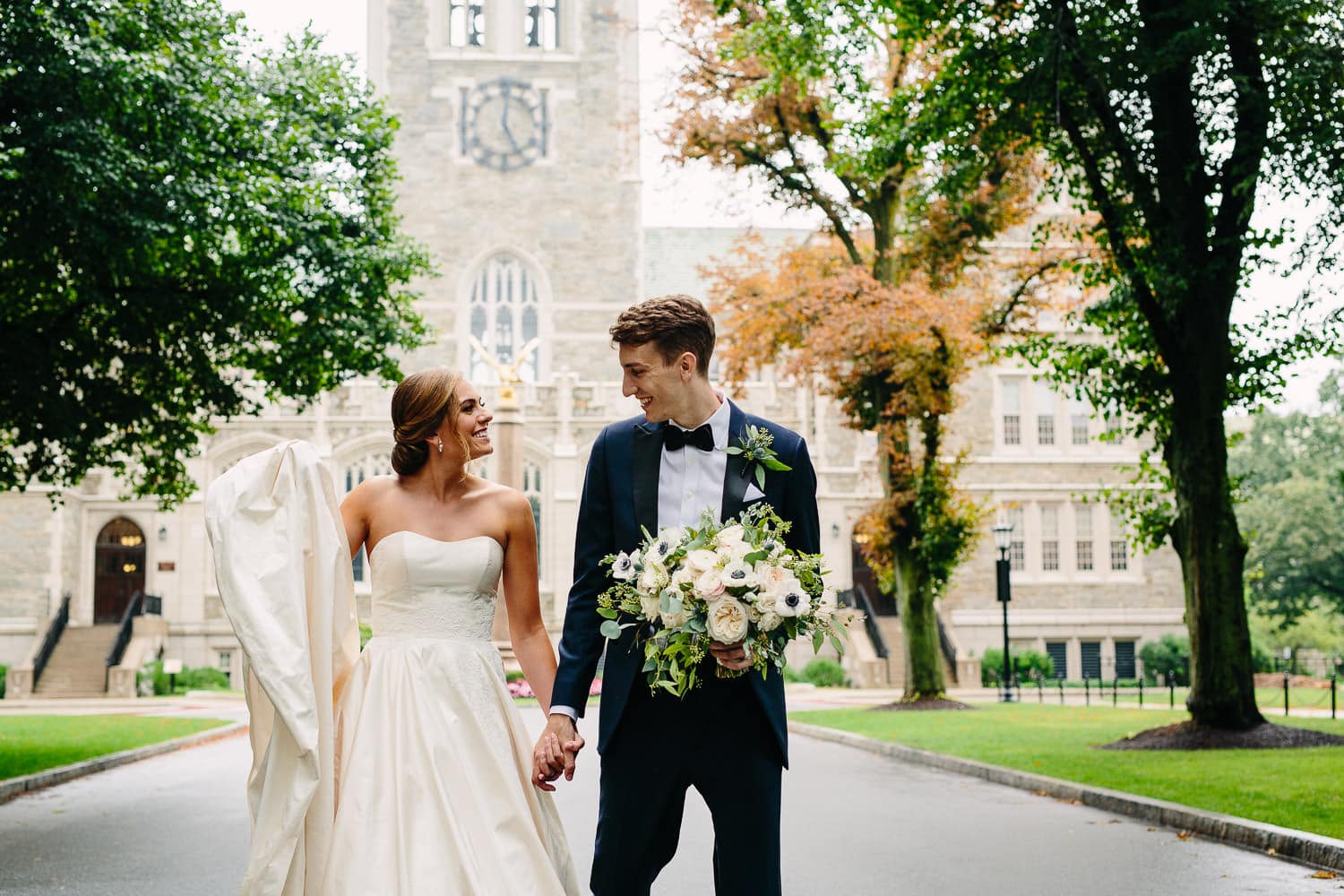 bride and groom share a laugh on Linden Lane, Boston College